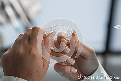 The dentist carefully holds the mouth guard in his hands, preparing for the procedure and demonstrating his adaptability Stock Photo