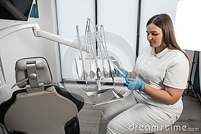 The dentist carefully prepares to receive patients in front of the dental chair in the medical center. In a dental Stock Photo