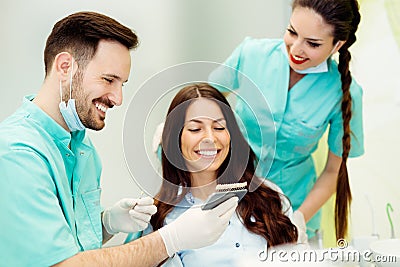 Dentist checking and selecting color of young woman`s teeth Stock Photo