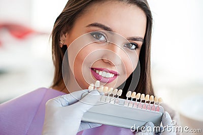 Dentist checking and selecting color of young woman`s teeth. Stock Photo