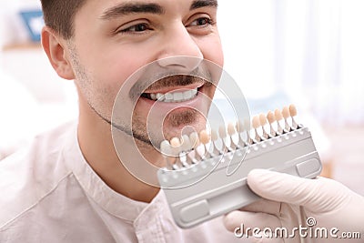 Dentist checking young man`s teeth color Stock Photo