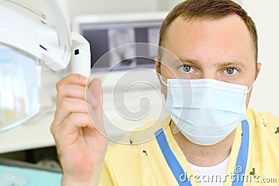 Dentist clings to lamp in dental clinic Stock Photo