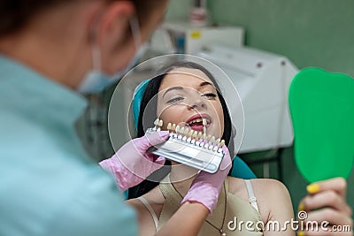 Dentist comparing patient's tooth with color sampler Stock Photo