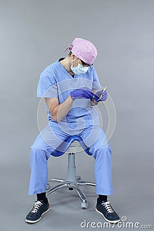 Dentist with dental instruments demonstrates typical unbalanced seated position at work Stock Photo