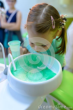 At the dentist dental patient girl spits water after treatment Stock Photo