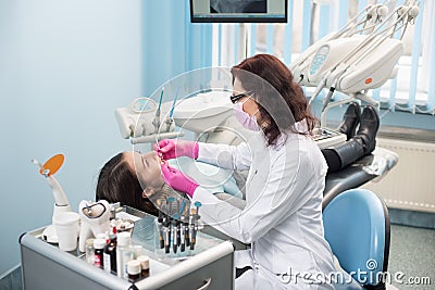 Dentist with dental tools - mirror and probe checking up patient teeth at dental clinic office. Medicine, dentistry Stock Photo