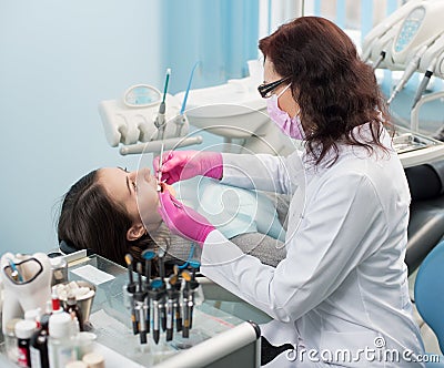 Dentist with dental tools - mirror and probe checking up patient teeth at dental clinic office. Medicine, dentistry Stock Photo