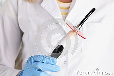 Dentist doctor holding curing light machine for caries treatment closeup Stock Photo