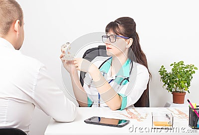 A dentist doctor tells a patient a man on the example of a model of a dental jaw and his disease. The concept of treatment of Stock Photo