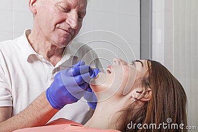 Dentist examines gums and teeth of his female patient Stock Photo