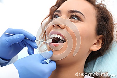 Dentist examining African-American woman`s teeth with mirror Stock Photo