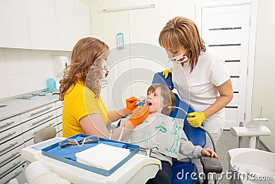 Dentist examining boy`s teeth in clinic. A small patient in the dental chair smiles. Stock Photo