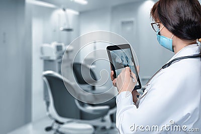 Dentist examining a tooth on a mobile tablet Stock Photo