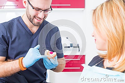 Dentist explaing dental treatment with denture to female patient Stock Photo