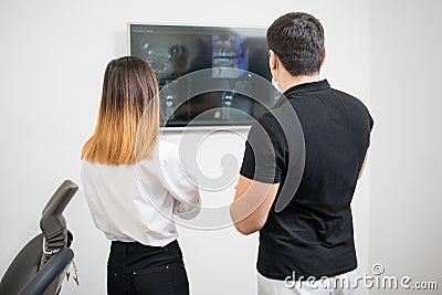 Dentist with female patient looking at dental x-ray image on computer screen Stock Photo