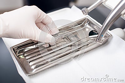 Dentist with gloved hand is picking dental tool in dental office Stock Photo