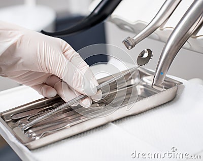 Dentist with gloved hand is picking dental tool in dental office Stock Photo