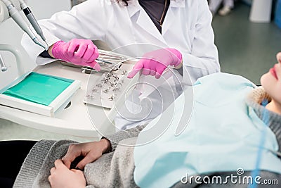 Dentist with gloved hands is treating patient with dental tools in dental office. Dentistry Stock Photo