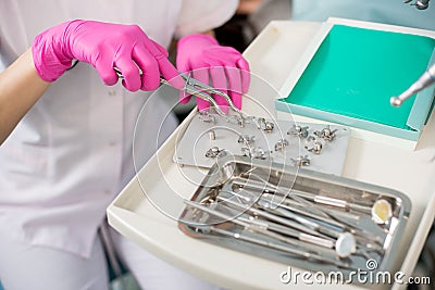 Dentist with gloved hands is working with dental devices in dental office. Dentistry Stock Photo