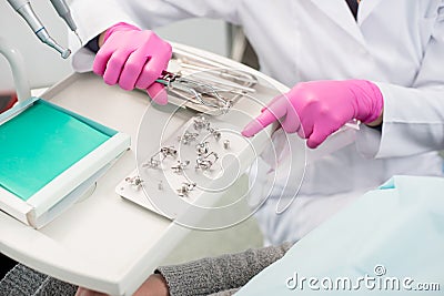 Dentist with gloved hands is working with dental tools in dental office. Dentistry Stock Photo