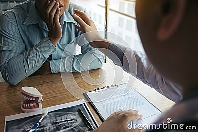 Dentist hand holding pen pointing x-ray picture and talking to the patient about medication and surgery treatment Stock Photo