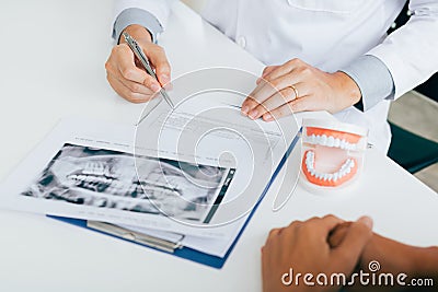 Dentist hand holding pen pointing x-ray picture and talking to t Stock Photo