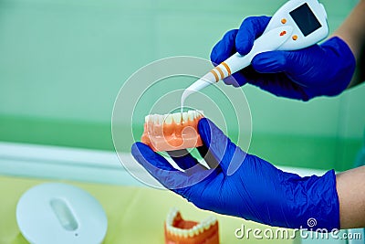 Dentist holding teeth model denture, showing with diagnostic periodontal probe and explaing to the patient what pulpitis looks lik Stock Photo