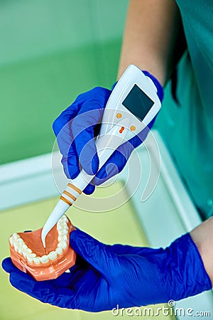 Dentist holding teeth model denture, showing with diagnostic periodontal probe and explaing to the patient what pulpitis looks lik Stock Photo