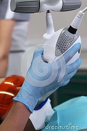 The dentist holds a lamp to whiten the tooth enamel.An unrecognizable person.Teeth whitening with cold light.Cosmetic Stock Photo