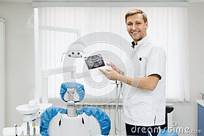 Dentist holds a photo of teeth in his hands while explaining Stock Photo