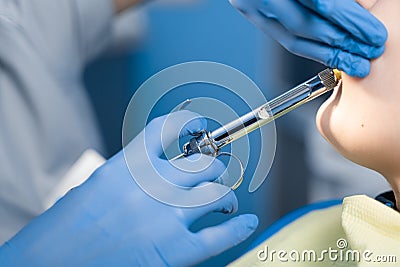 Dentist injects anesthesia syringe of the diseased teeth for the patient. Caries treatment. Stock Photo