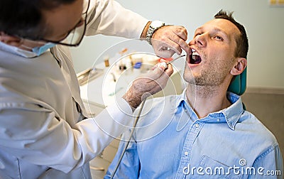 Dentist Inspecting Teeth Of Young Man. Stock Photo