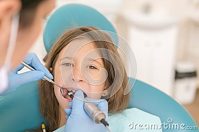 dentist and little girl patient. Close-up of pretty little girl opening his mouth wide during inspection of oral cavity at the Stock Photo