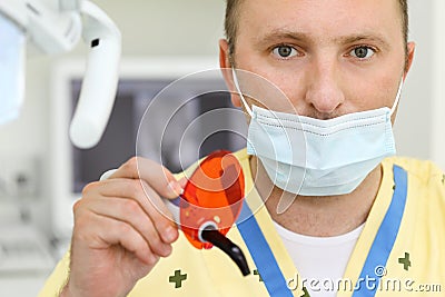 Dentist in mask with ultraviolet curing light tool Stock Photo