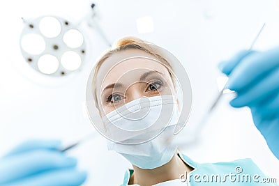 Dentist in medical mask working in clinic and looking at camera Stock Photo