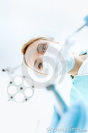 Dentist in medical mask working in clinic and looking at camera Stock Photo