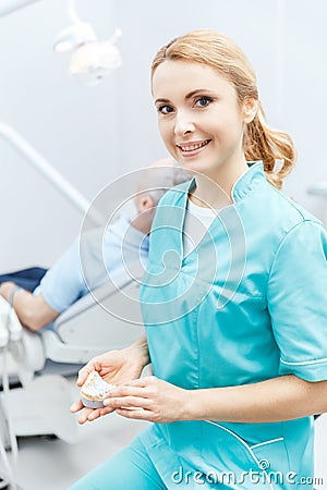 Dentist in medical uniform sitting in clinic and smiling at camera Stock Photo