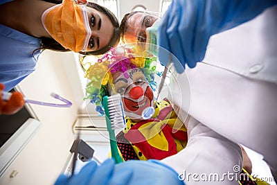 Dentist with nurse working in bottom view with clown holding too Stock Photo