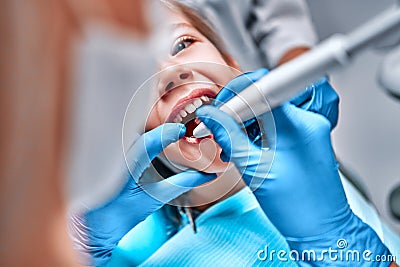 Dentist performing dental filling procedure to preteen girl in pediatric dental clinic Stock Photo