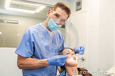 Dentist performing teeth treatment with female patient open mouth Stock Photo