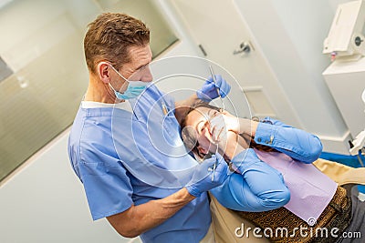 Dentist performing teeth treatment with scared female patient Stock Photo