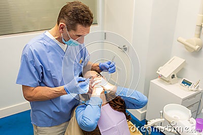 Dentist performing teeth treatment with scared female patient Stock Photo