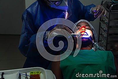 Dentist performing a teeth whitening procedure with a client Stock Photo