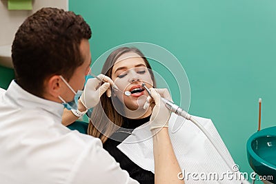 Dentist performs professional polishing of tooth enamel for woman patient Stock Photo