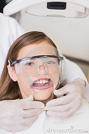 Dentist putting mouth retractor on little girl Stock Photo