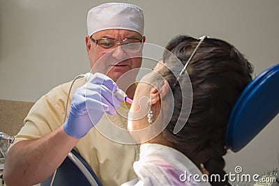 The dentist shines a UV light seal to a woman in a private clinic Editorial Stock Photo