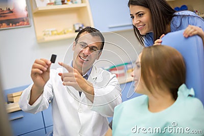 Dentist show dental film to patient and dental technician Stock Photo