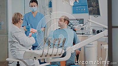 Dentist showing correct way to clean denture with toothbrush Stock Photo