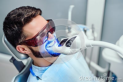 Dentist starting teeth whitening procedure with young man Stock Photo