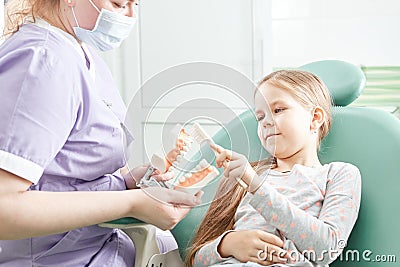 Dentist teaching girl how to brush teeth. Pediatric dentist educating a child about tooth-brushing on a model Stock Photo